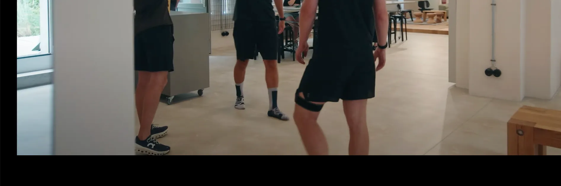 Employees walking through On's office in running shoes and athletic socks, seen from knee level